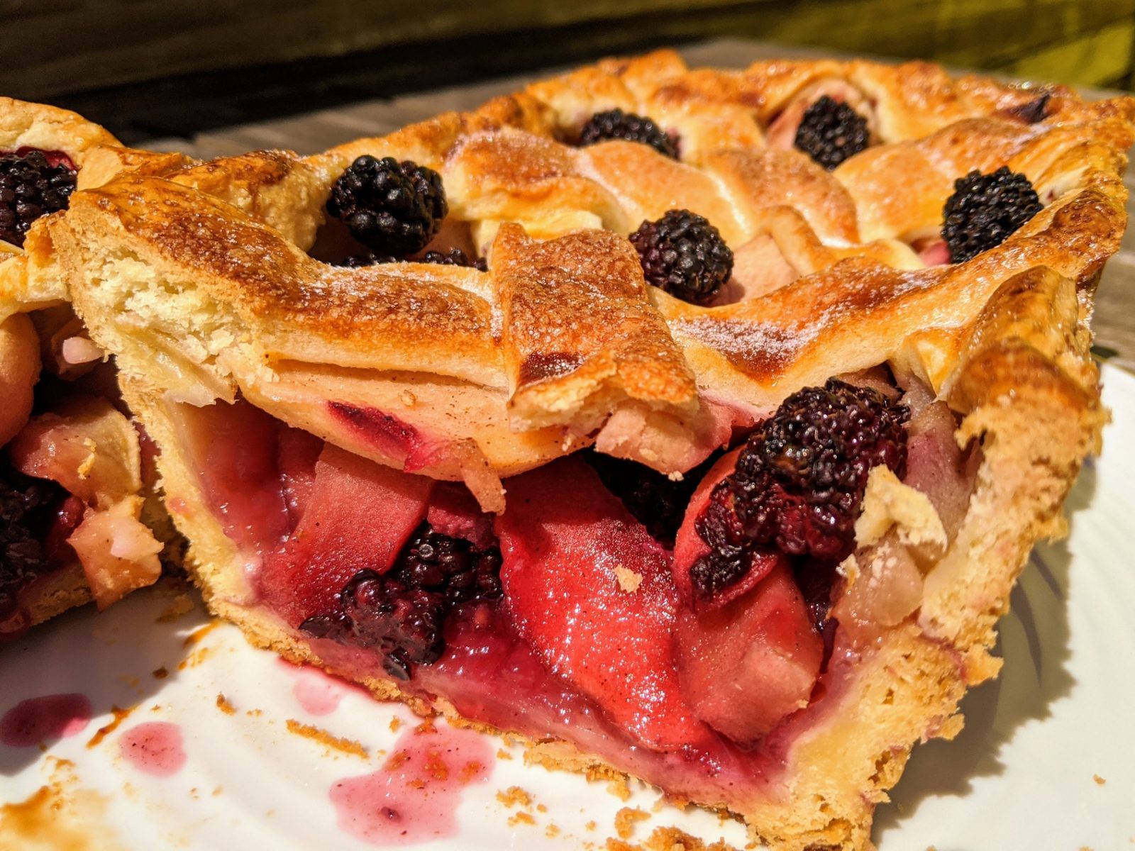 A slice of blackberry and apple pie with a golden lattice crust