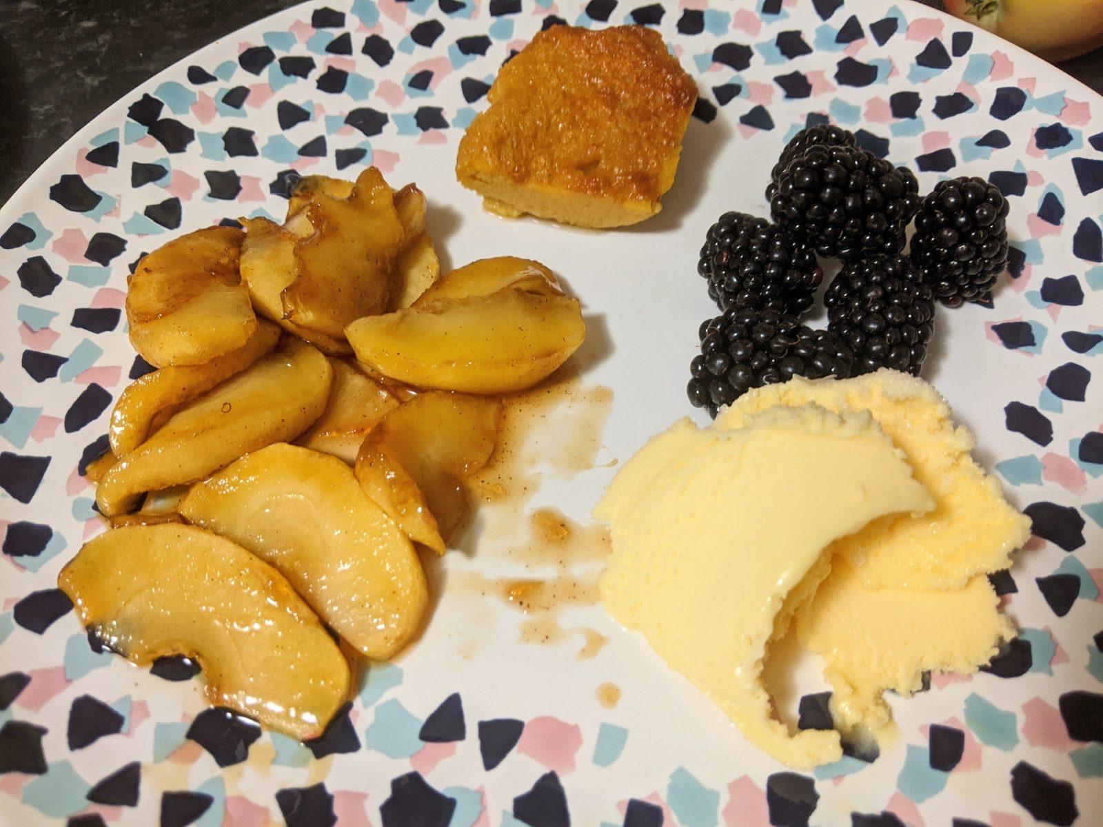 Spiced apples, blackberries and cream on a terrazzo-patterned plate