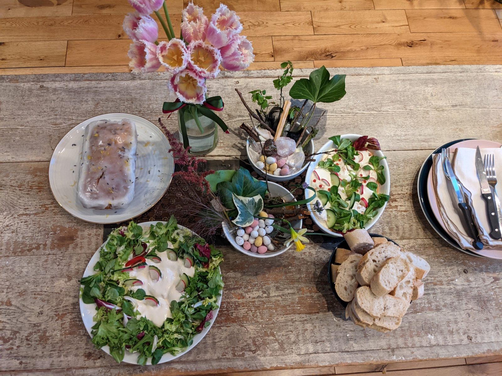 A spring feast table with tulips, salad, bread and lemon cake