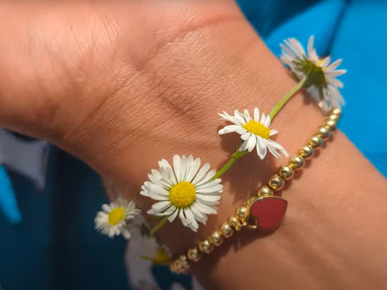 A daisy chain worn as a bracelet on a sunlit wrist